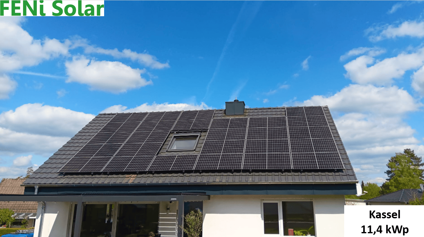 Ein weißes Haus mit Solarmodulen auf dem Dach unter blauem Himmel in Kassel.