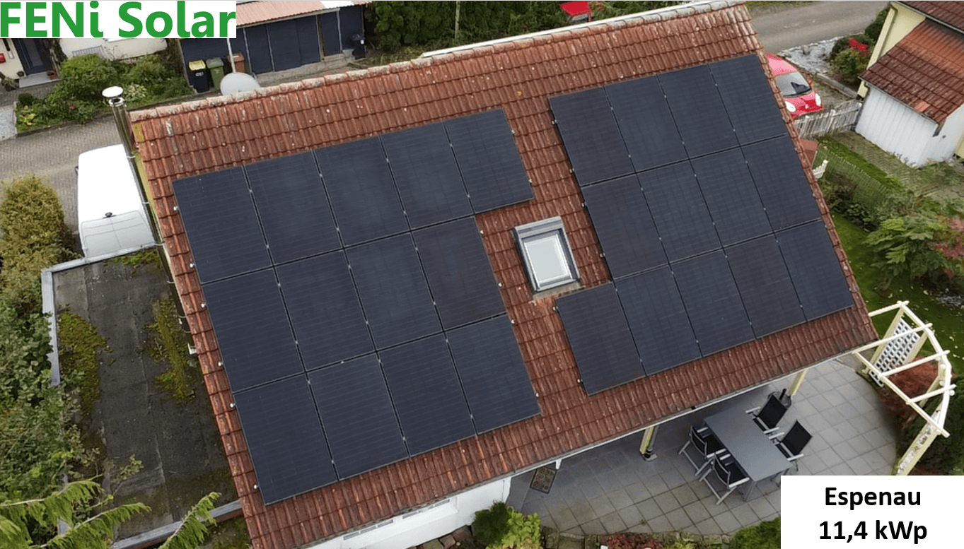 Eine Dachansicht mit Solarmodulen, umgeben von grünen Pflanzen. Text: "FENi Solar, Espenau 11,4 kWp".