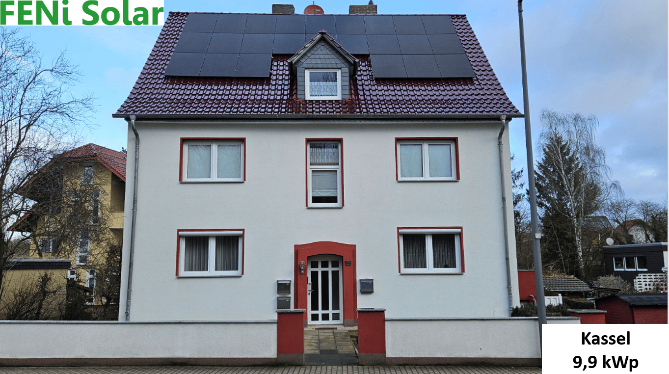 Ein zweistöckiges Haus mit Solarpaneelen auf dem Dach, weiß mit roten Akzenten, steht in Kassel.