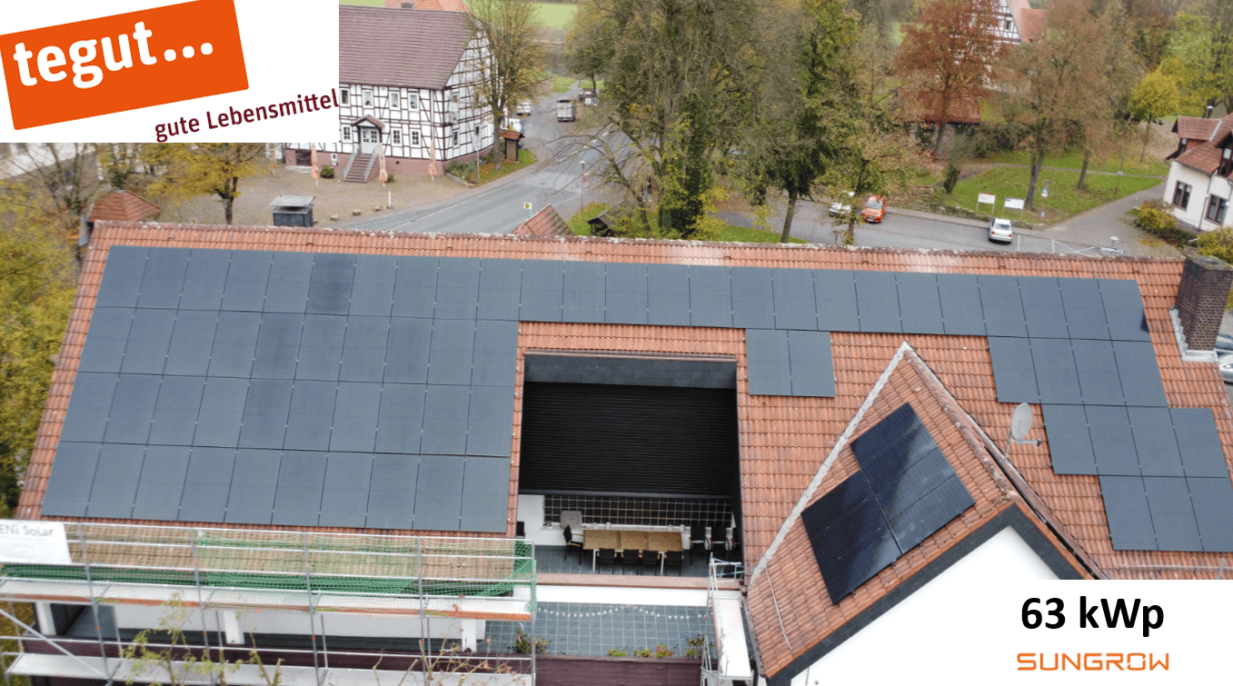 Dach mit Solaranlagen, 63 kWp, umgeben von Fachwerkhäusern, herbstliche Bäume, Tegut-Werbung oben links.